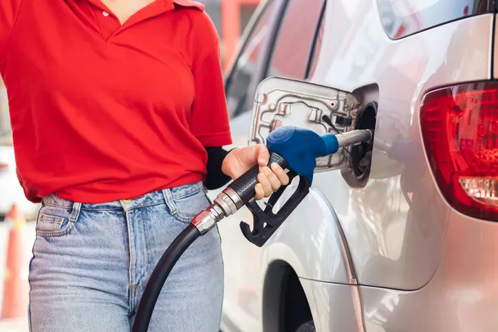 Kobieta wlewająca paliwo do baku auta.