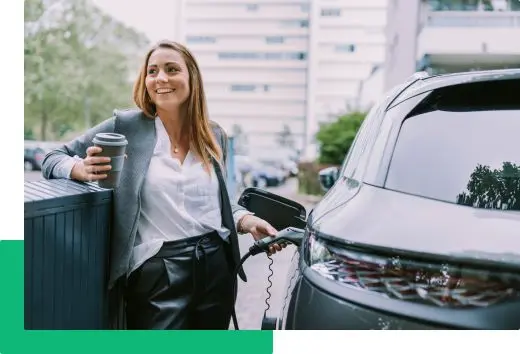 Kobieta z kubkiem kawy ładuje samochód elektryczny